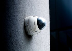 Close-up view of a dome security camera mounted on a concrete wall for surveillance.
