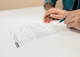 Close-up of hands signing adoption papers in an office environment, symbolizing family and legal process.